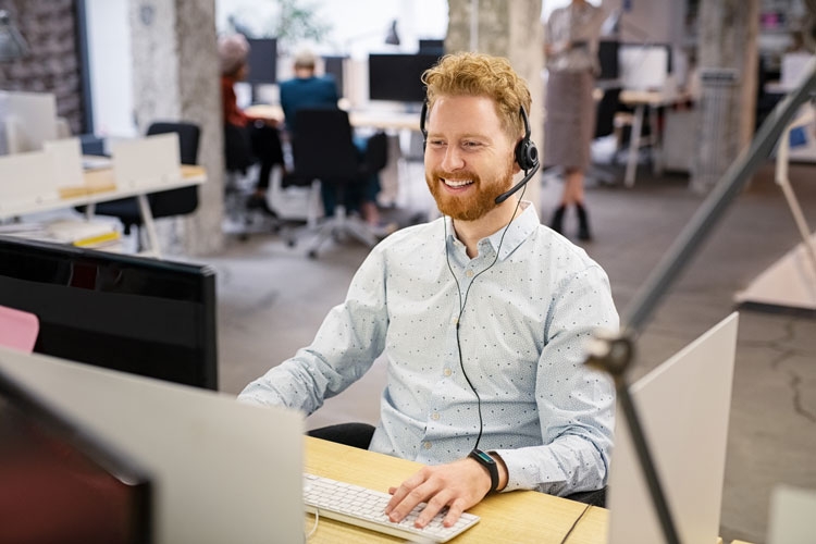 A man sitting at a call centre desk speaking on the phone